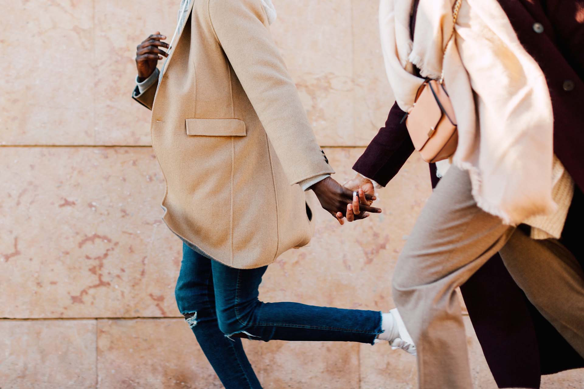 Friends holding hands and running along the street.